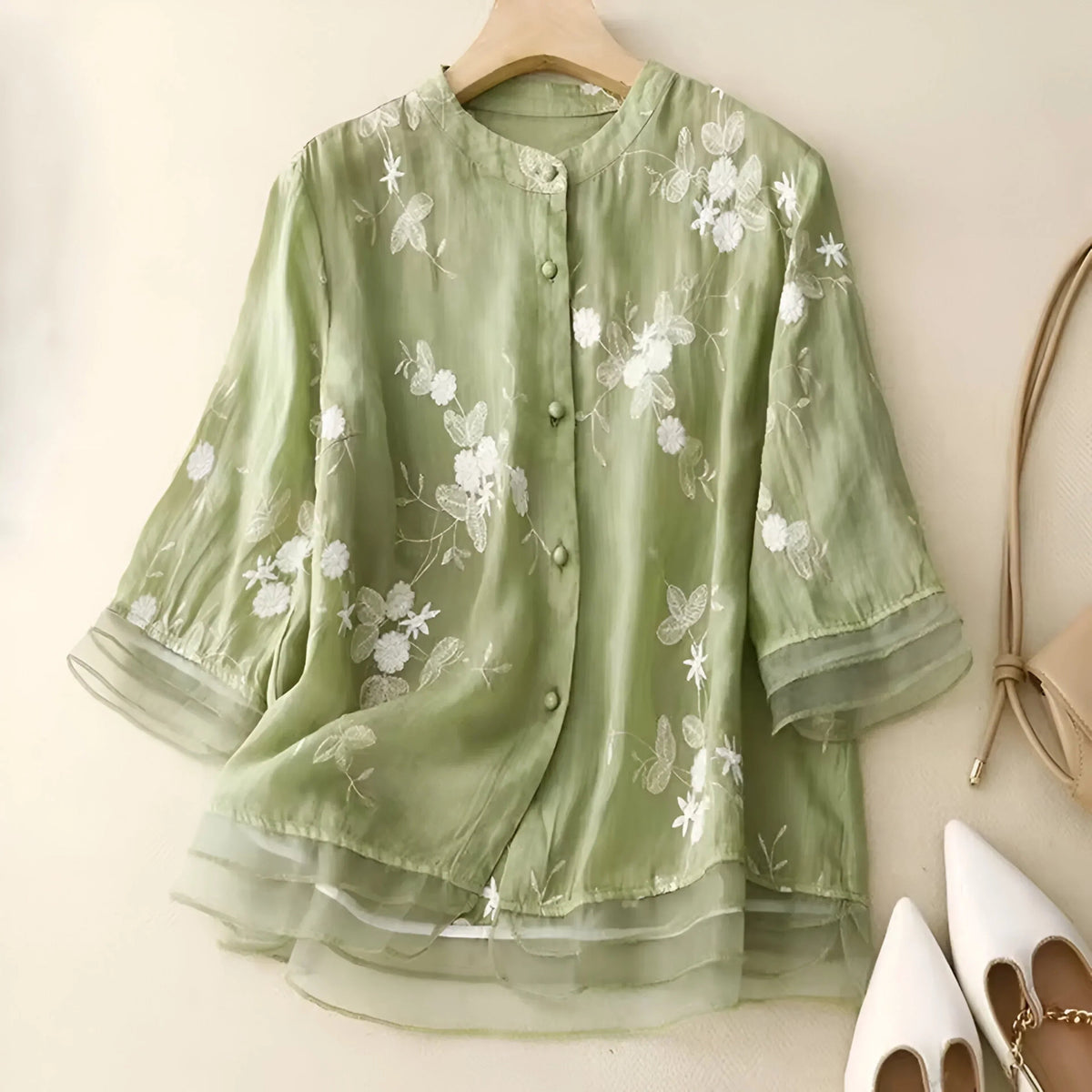 Blouse transparente à broderies florales portée, ourlet évasé, manches mi-longues