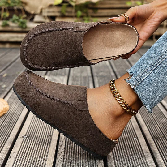 Side view of women's suede slip-on clogs showing flat sole and open heel construction