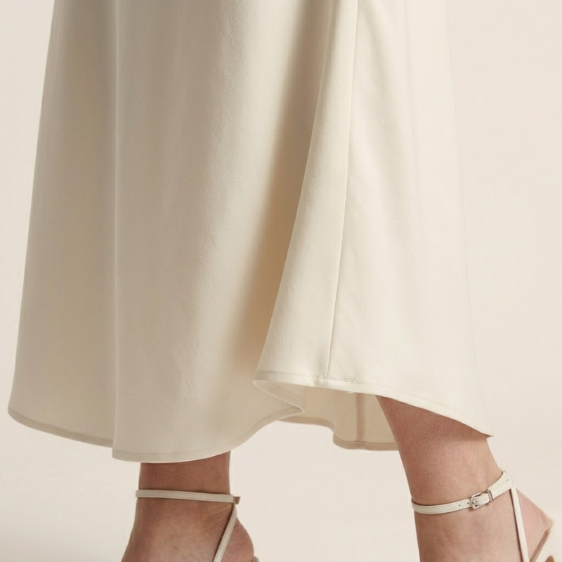 Jupe en satin mi-longue coupe biais, taille haute, drapé élégant