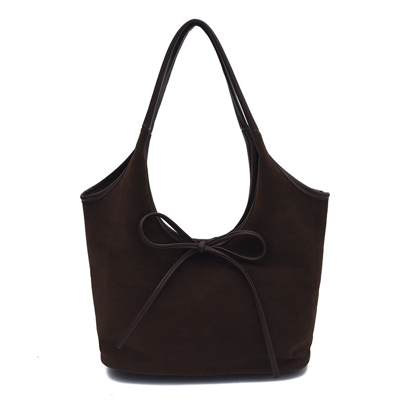 Minimalist faux suede tote bag with bow accent, shown as everyday shoulder bag